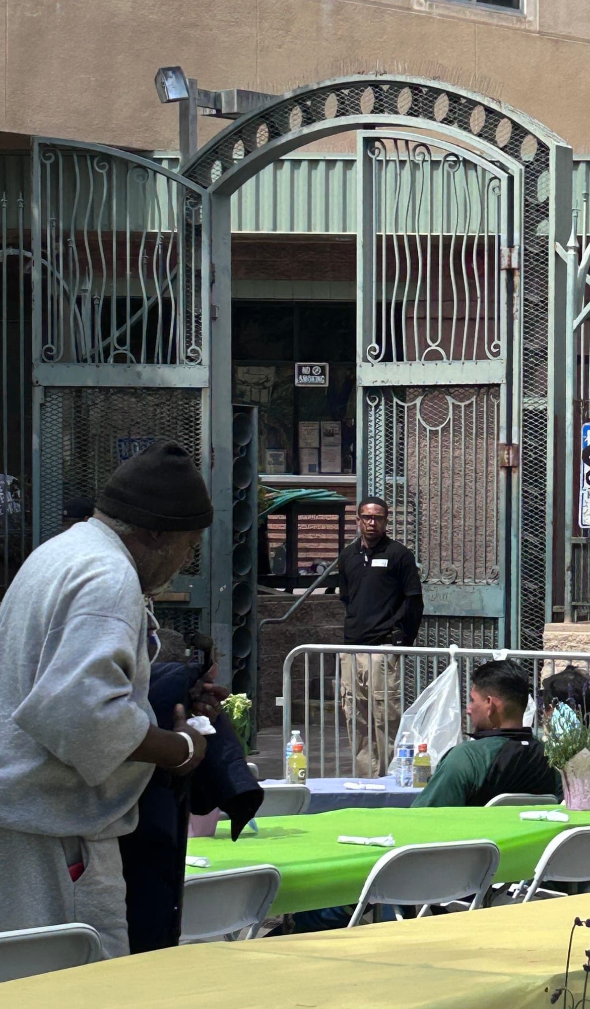 A guest being served at the arched entrance of the Los Angeles Mission, with a PSLA Worldwide officer standing post at the doorway